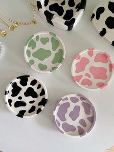 four plates with different designs on them are sitting on a table next to a necklace