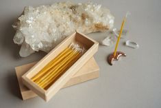 a wooden box filled with yellow sticks next to some crystal rocks and a pair of scissors