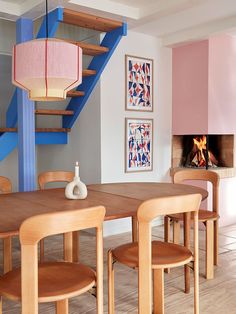 a dining room table with four chairs and a fire place in the back ground area