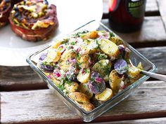 a glass bowl filled with potato salad on top of a wooden table