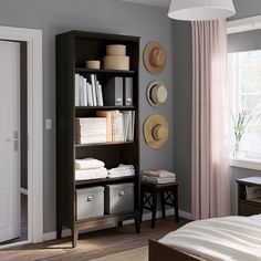 a bedroom with gray walls and white bedding, bookshelf filled with items