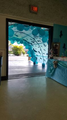 an open door to a room with balloons on the wall and blue curtains behind it