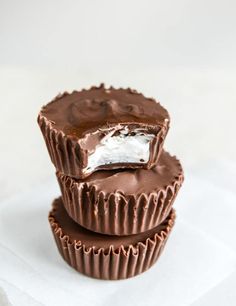 three chocolate cups stacked on top of each other with white frosting in the middle