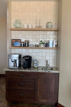 a coffee maker on top of a wooden cabinet in front of a wall with shelves