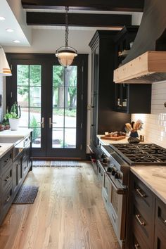 a kitchen with black cabinets and white counter tops, wood floors and an open door leading to the patio