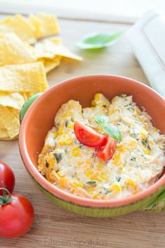 a bowl of dip with tomatoes and tortilla chips