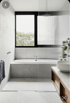 a bathroom with a tub, sink and large window