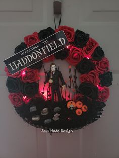 a halloween wreath decorated with fake roses and a creepy doll in front of the sign that says welcome to haddonfield