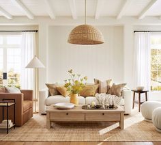 a living room with couches, chairs and tables in front of two large windows