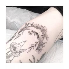 a woman's leg with flowers and a crescent tattoo on it