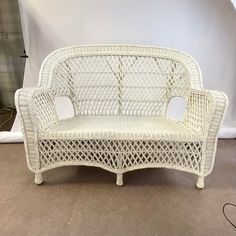 a white wicker couch sitting on top of a carpeted floor next to a wall