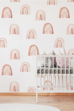 a baby's crib in front of a wall with pastel rainbows on it