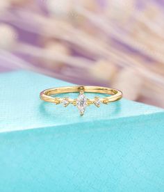 a yellow gold ring with three pear shaped diamonds sitting on top of a blue box