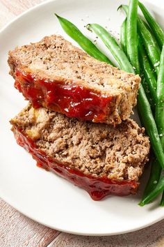 two slices of meatloaf on a plate with green beans