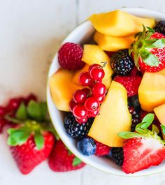 a white bowl filled with lots of different types of fruit on top of a table