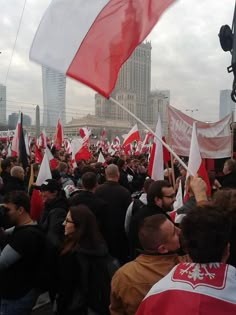 a large group of people holding red and white flags