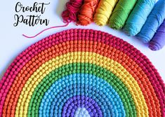 the crochet rainbow rug is next to several skeins of yarn and thread