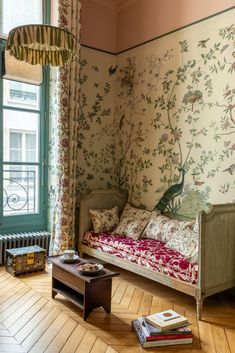 a room with a bed, table and wallpaper on the walls in it's corner