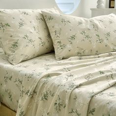 a bed with white sheets and green flowers on it