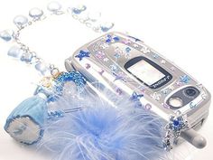 an old cell phone is decorated with blue beads and feathers as well as a chain