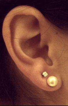 a close up of a person's ear with two pearls