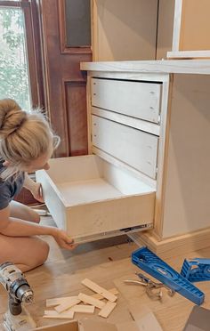 a woman kneeling down next to a drawer full of cut up wood planks and tools