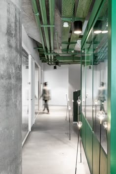 a person walking down a long hallway in an office building with green and white walls