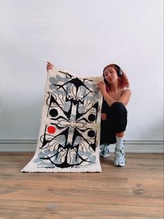 a woman sitting on the floor next to a large piece of art that looks like an abstract painting