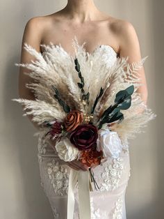 a woman in a wedding dress holding a bouquet with feathers and flowers on it's back