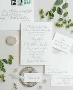 the wedding stationery is laid out with greenery