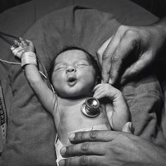 a black and white photo of a baby being examined