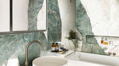 a white tub sitting next to a bathroom sink under a mirror in front of a wall