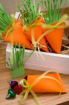 three carrots with green grass in them on a table next to some candies