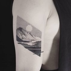 a man's arm with a mountain and sun tattoo on the left upper arm