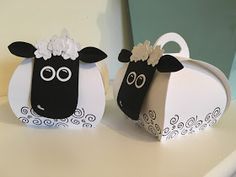 two black and white sheep are standing next to each other on a table with paper