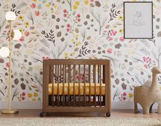 a baby crib in front of a floral wallpaper