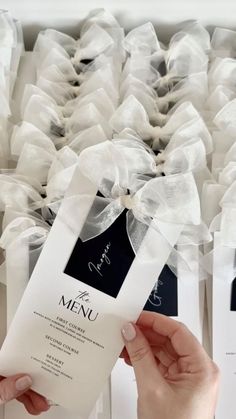 a person holding up a menu in front of some white boxes with bows on them