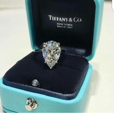 a diamond ring in a blue box on a white surface with the words tiffany & co written below it