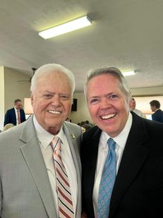 two men in suits and ties smiling for the camera