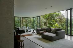 a living room filled with furniture and lots of glass doors leading to the trees outside