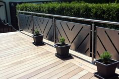 three potted plants sitting on top of a wooden floor next to a metal fence