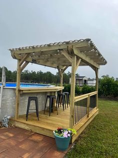 a wooden gazebo sitting on top of a lush green field next to a swimming pool