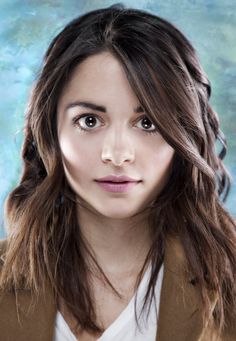 a woman with long hair and brown blazer posing for a photo in front of a blue background