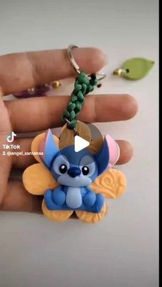 a hand holding a tiny keychain with a little blue devil charm on it