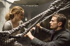 a man and woman standing next to each other in a room with ropes on the wall