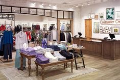 a clothing store with lots of clothes on display in the front and behind it is a wooden table