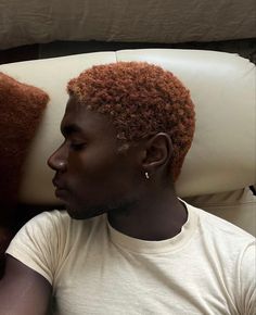 a man sitting on top of a white couch next to a brown pillow and pillows