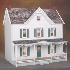 a white doll house with green shutters and windows