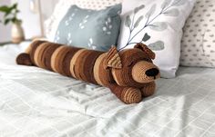 a stuffed animal laying on top of a bed next to pillows and pillowcases