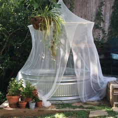 an outdoor gazebo with mosquito netting and potted plants